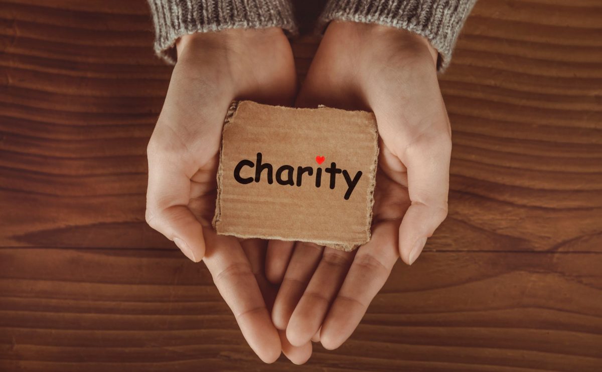 Hands holding block of wood that reads: Charity