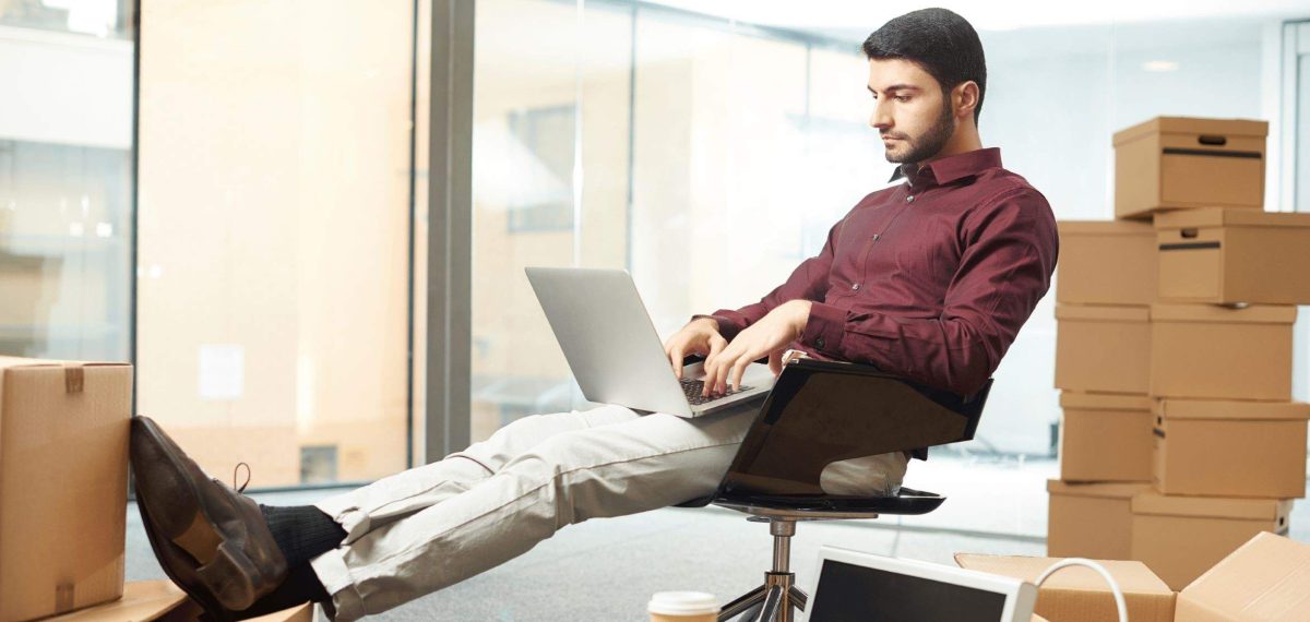 Man with laptop surrounded by boxes starting a business following legal advice