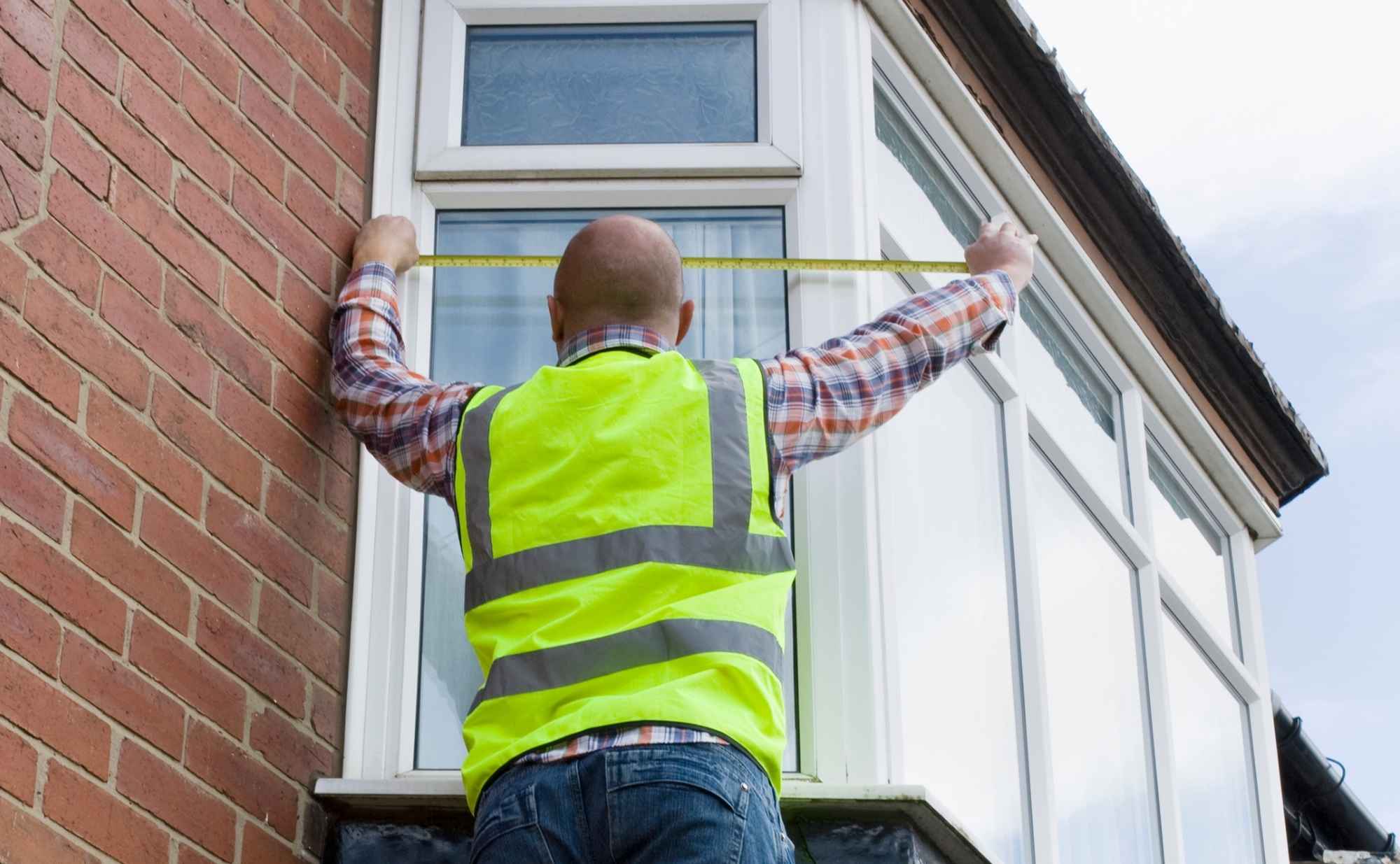 A surveyor measuring a window.